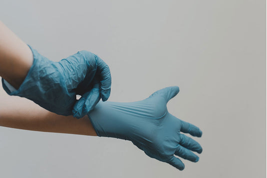 Person putting on blue rubber gloves