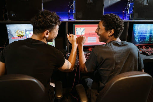 Two happy PC gamers fist-bumping each other while playing.