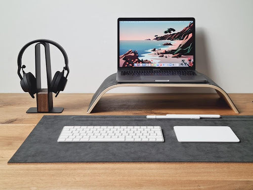 A large, gray desk mat on a wooden desk setup.